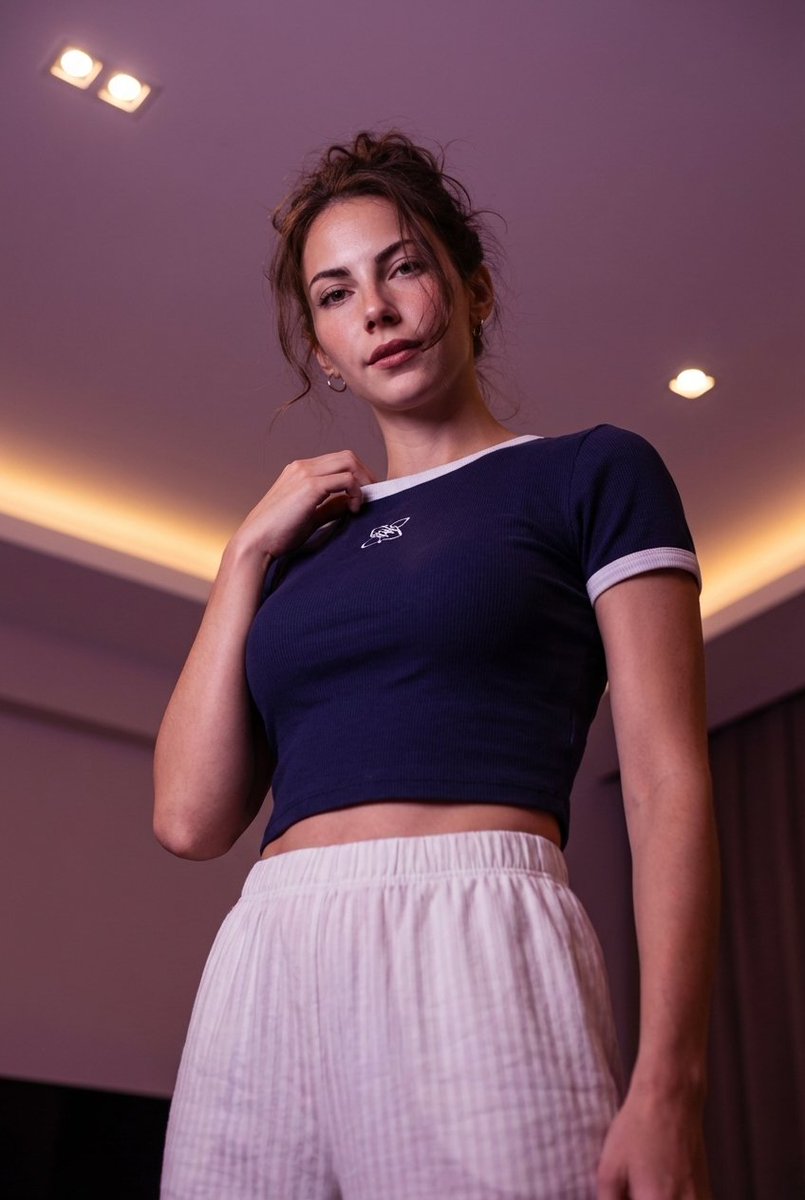 Low-angle stylized portrait of a young woman in a dim room — output 1